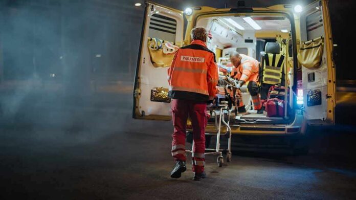 Paramedics load a patient into an ambulance at night