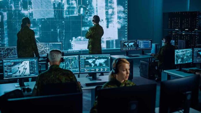 Military analysts monitor data on multiple screens in a command center