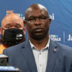 Man in suit and glasses at a press conference