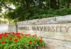 Cornell University stone entrance sign with red flowers