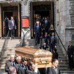 Pallbearers carry a casket down church steps