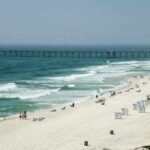Sandy beach with turquoise waves and a long pier