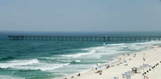 Sandy beach with turquoise waves and a long pier