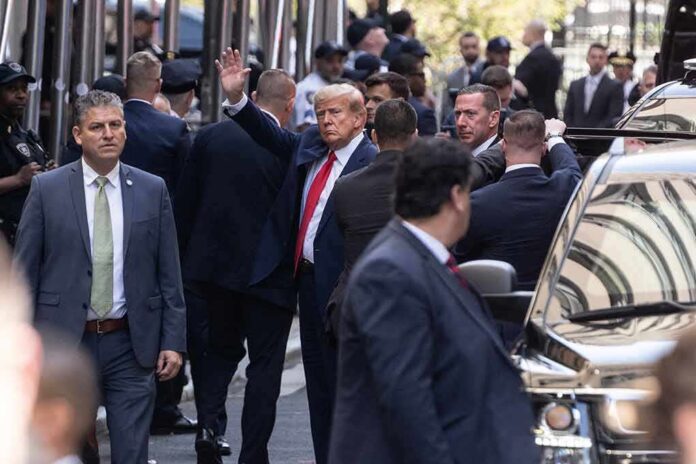 Donald Trump waving while surrounded by security personnel on a city street