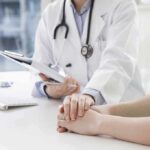 Doctor holding a patient's hands during consultation