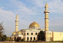 Mosque with golden dome and two tall minarets under a partly cloudy sky