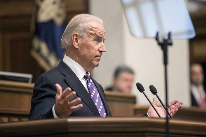 shutterstock_348822884 Joe Biden speaking at a podium with hands raised