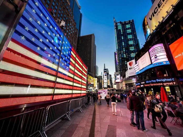 American flag LED display in a busy city square at dusk