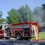 Fire truck parked on suburban street with hoses deployed