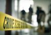 Crime scene tape with investigators in the background