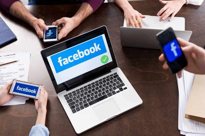 Laptop with Facebook on screen surrounded by smartphones