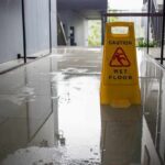Yellow wet floor caution sign on a shiny wet hallway