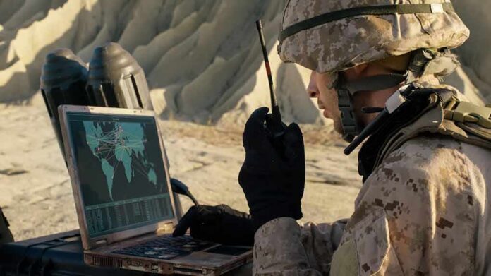 soldier using a rugged laptop and radio in a desert setting
