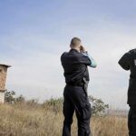 Two border police officers scan the horizon near a watchtower