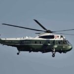 Green and white helicopter in flight