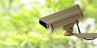 A security camera mounted outdoors with a blurred green background