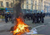 Fire burning on the street amid police presence.