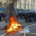 Fire burning on the street amid police presence.