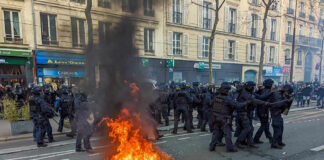 Fire burning on the street amid police presence.