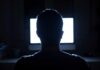 person silhouetted in front of a bright computer screen
