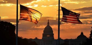 U.S. Capitol silhouette with American flags at sunset