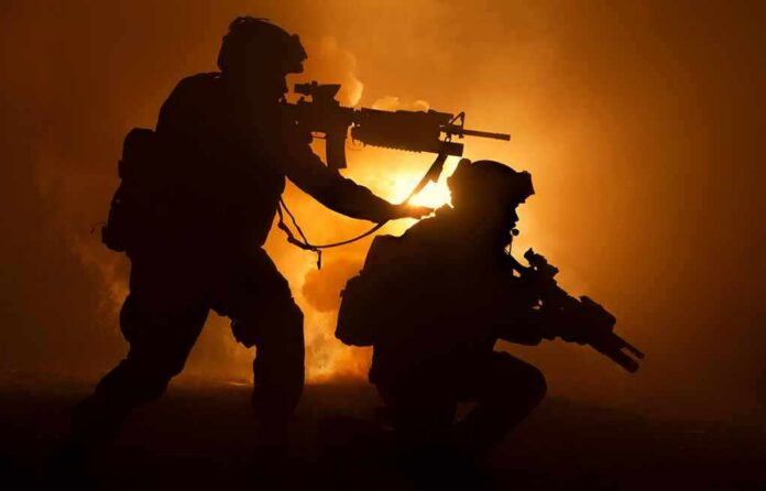 shutterstock_1163416795 Two armed soldiers silhouetted against fiery smoke