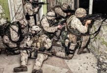 soldiers in camouflage gear take positions inside a damaged building