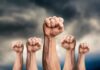 Raised fists against a cloudy sky