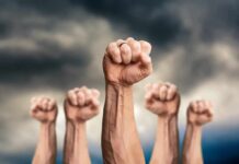 Raised fists against a cloudy sky
