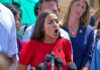 Judy Chu among crowd as a woman in red speaks at outdoor press event