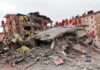 Rescue workers in orange uniforms on a collapsed building site after an earthquake