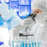 Scientist in protective suit using a microscope