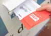 Election Shock: USPS Rule Gets Hammered Hand dropping mail-in ballots into a drop box