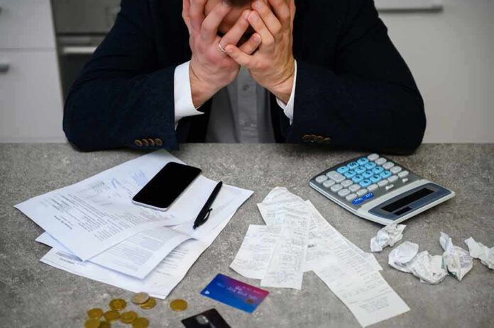 Stressed person with head in hands at a desk with bills and calculator