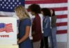 Quiet Ticket-Splitters Could Flip Michigan Voters at booths with American flags in a polling place