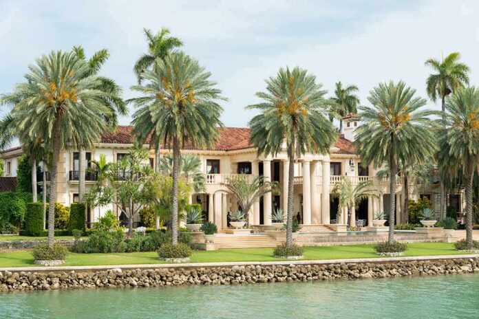 Waterfront mansion with palm trees and grand columns