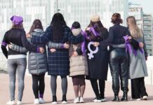 Group of women standing arm in arm with purple ribbons