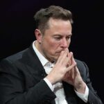 Elon Musk seated with hands steepled in thought