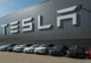 Tesla cars parked outside a large Tesla building