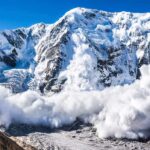 Snow avalanche sweeping down a rugged mountain