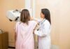 Technician assists patient with mammogram machine