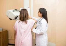Technician assists patient with mammogram machine