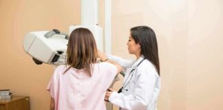 Technician assists patient with mammogram machine