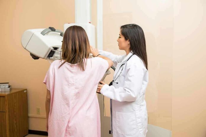 Technician assists patient with mammogram machine