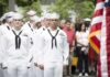 Dontrelle Inman and Anthony C. Ferrante among U.S. Navy sailors at a ceremony with an American flag