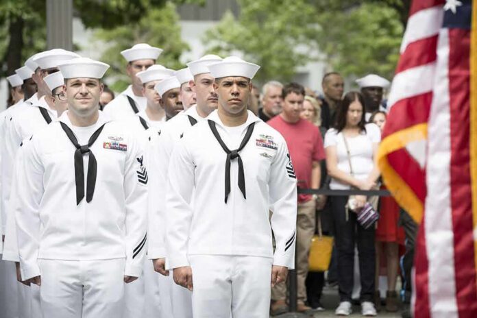 Dontrelle Inman and Anthony C. Ferrante among U.S. Navy sailors at a ceremony with an American flag