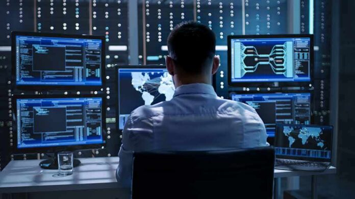 IT professional monitors multiple screens in a server room
