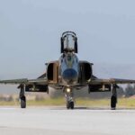 Military jet taxiing on runway with open canopy