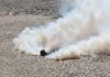 Smoke grenade releasing a thick cloud on a cobblestone street