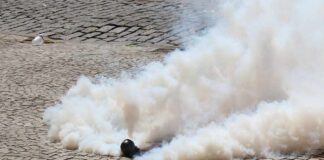 Smoke grenade releasing a thick cloud on a cobblestone street